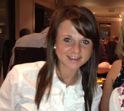 Woman smiling in a restaurant setting.