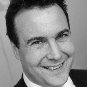 Smiling person in a suit, black and white portrait.