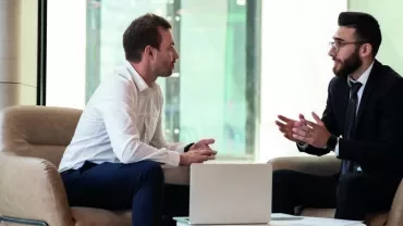 Deux hommes discutent dans un bureau moderne.