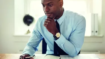 Man in blue shirt working on laptop at desk
