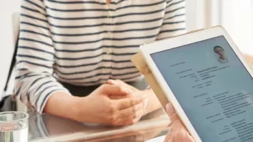 Person holding tablet with resume during interview.