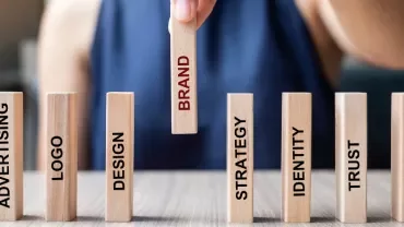 Hand picking wooden block labeled 'Brand' among others.