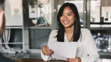 Woman smiling at a table during an office meeting.