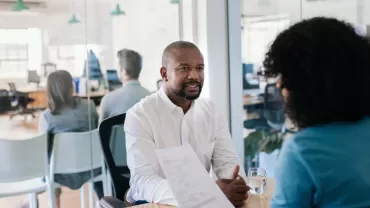 Two people having a discussion in a modern office setting.