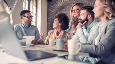 A group of people having a lively discussion in a modern office setting.