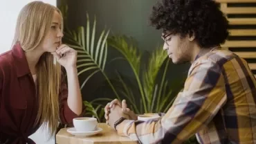 Two people having a serious conversation at a cafe table.