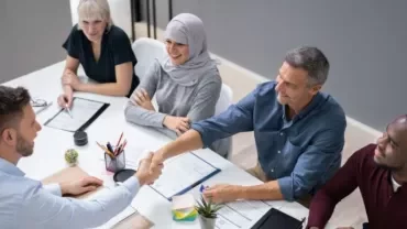 Diverse group in a meeting room shaking hands