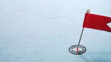 Small red flag on pin stuck into blue textured surface.