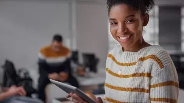 Smiling woman holding a tablet in an office