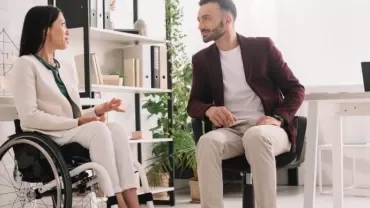 Two colleagues having a discussion in a bright, modern office.