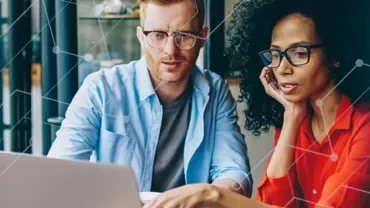 Two people collaborating on a laptop in an office.