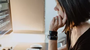 Woman focusing on computer screen displaying code.