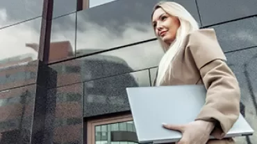 person walking with the laptop closed in the hand