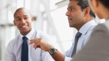 Three professionals having a discussion in an office setting.