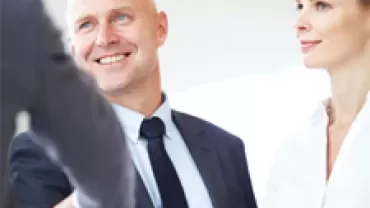 Two businesspeople smiling during a handshake.