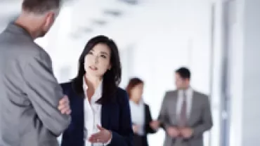 Business professionals having a conversation in an office hallway.