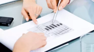 Two people discussing a graph chart at a meeting table.