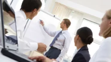 Business meeting with a man presenting at a whiteboard.
