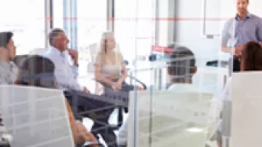 A team meeting in a modern office setting with a person presenting.