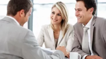 Three professionals having a discussion at a table.