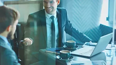 Deux hommes en réunion d'affaires avec un ordinateur portable et du café.