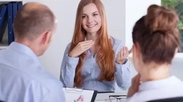 Smiling woman in a meeting with two colleagues, discussing a document.