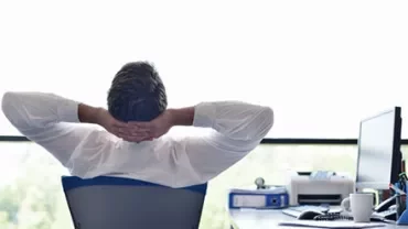 Man relaxing at desk, looking out the window.
