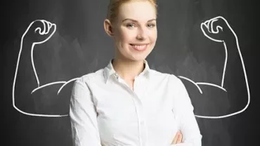 Confident woman with drawn muscular arms on a chalkboard