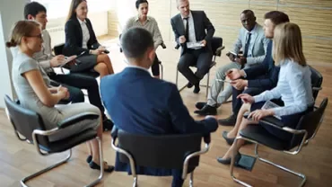 Group of people sitting in a circle having a meeting.