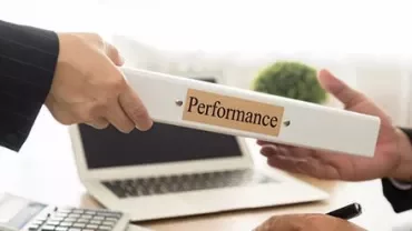Deux mains échangent un classeur intitulé 'Performance' dans un bureau.
