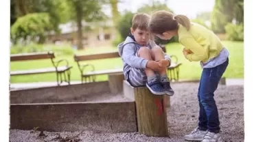 A girl comforts a boy in a playground.