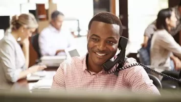 Homme souriant au téléphone dans un bureau animé.