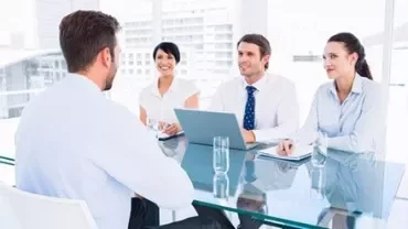 Réunion d'affaires dans un bureau moderne avec quatre personnes autour d'une table.