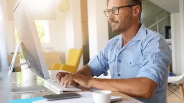 Man typing on computer in bright living room