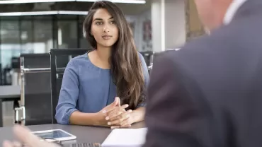 Woman in blue shirt at office meeting table.