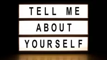 A lightbox sign displaying 'Tell me about yourself' in bold letters.