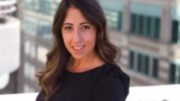Woman smiling with city buildings in the background.