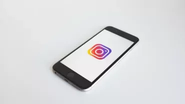 Smartphone laying on white surface displaying Instagram logo.