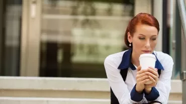 Woman sitting on steps holding a coffee cup.