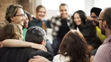 Groupe de personnes assises en cercle, souriantes et s'embrassant.