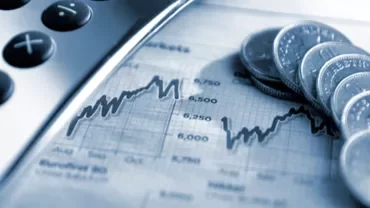 Calculator and coins on a financial graph.