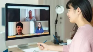 Woman participating in a video conference on a desktop computer.