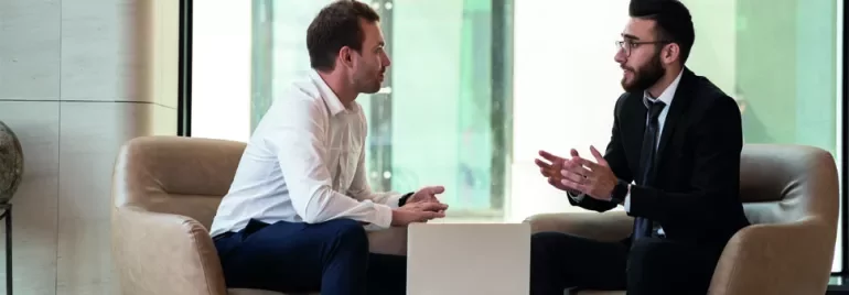 Deux hommes discutent dans un bureau moderne.