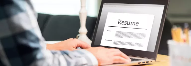 Person typing a resume on a laptop at a desk.