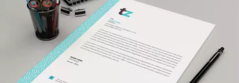 Mockup of a letter on a desk with pens and a notebook.