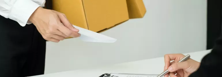 Person handing a document to another person signing a contract.