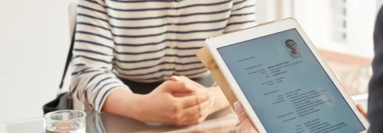 Person holding tablet with resume during interview.
