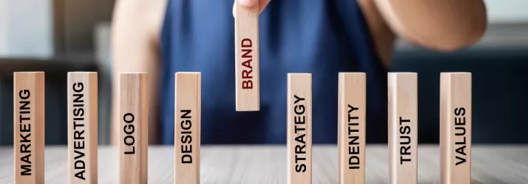 Hand picking wooden block labeled 'Brand' among others.