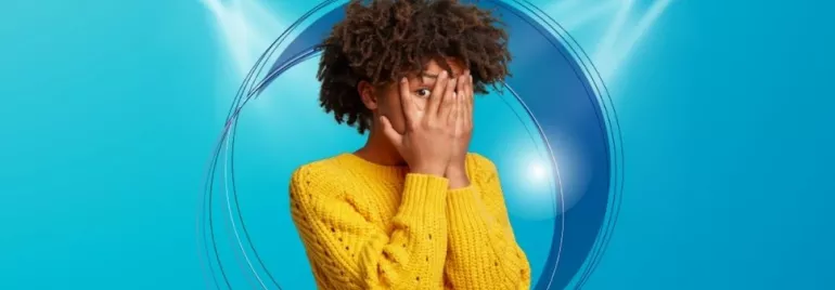 Personne en pull jaune avec les mains sur le visage sur un fond bleu.
