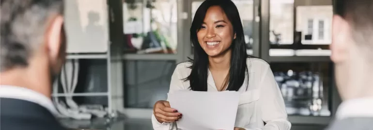 Woman smiling at a table during an office meeting.